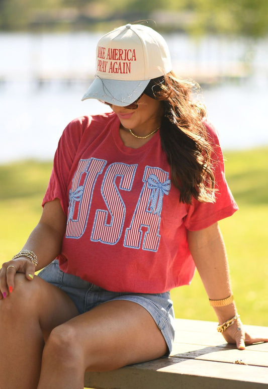Woman wearing heather red USA patriotic bow graphic t-shirt styled with denim shorts outdoors in summer