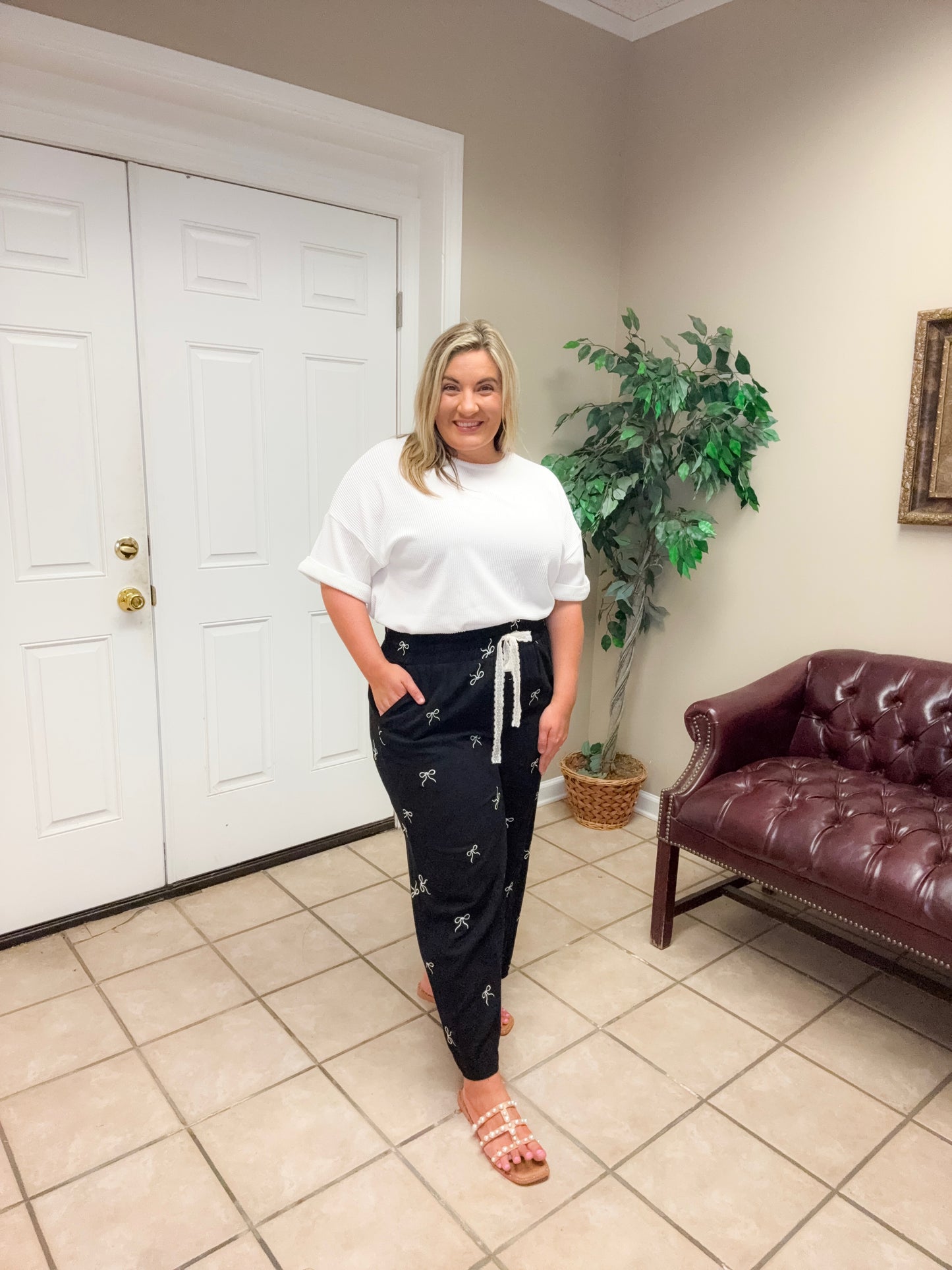 Woman wearing black wide leg linen blend pants with bow print and drawstring waist styled casually indoors