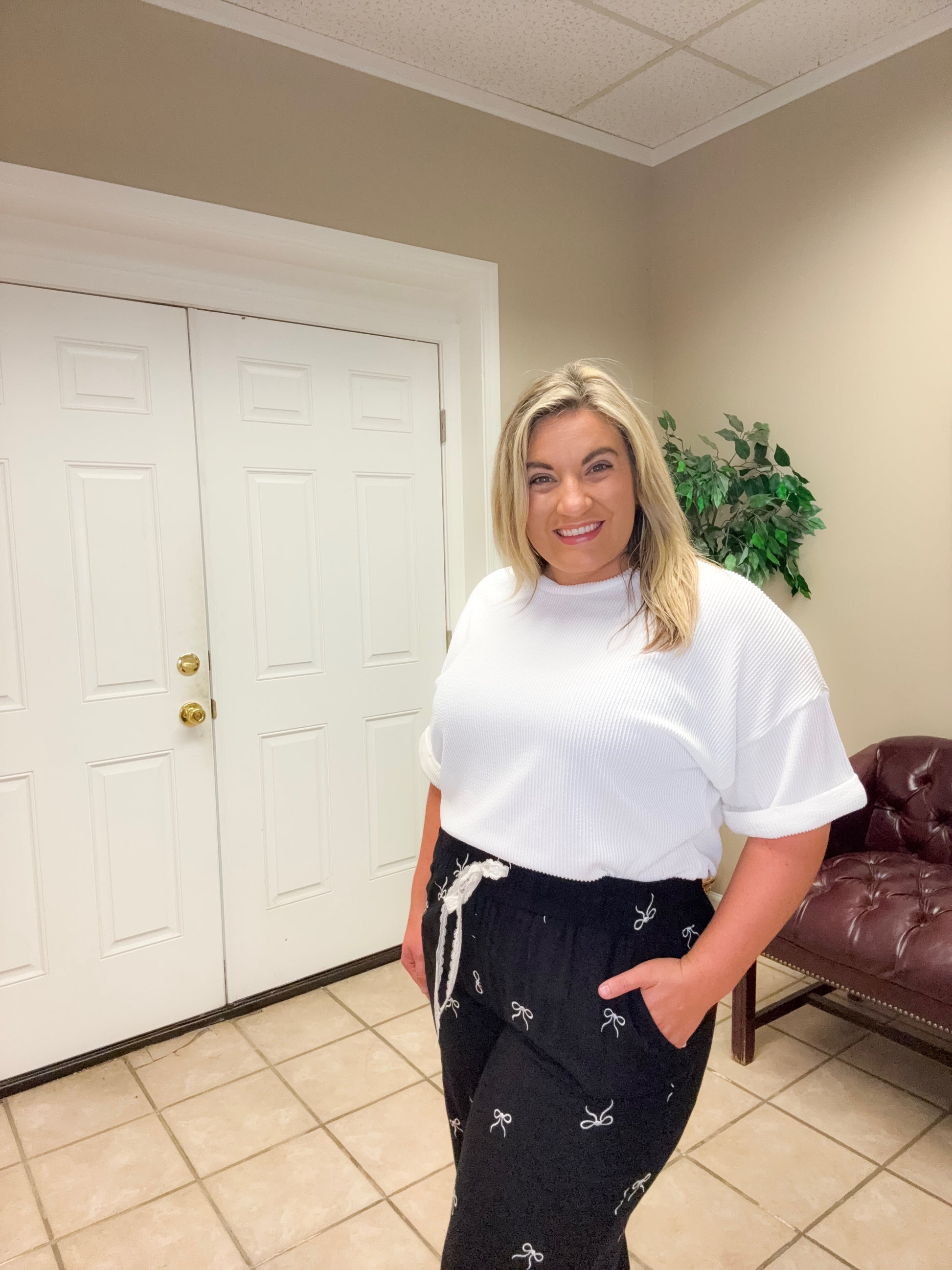 Woman wearing black wide leg linen blend pants with bow print and drawstring waist styled casually indoors