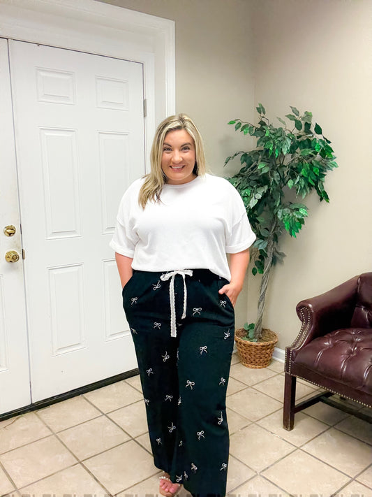 Woman wearing black wide leg linen blend pants with bow print and drawstring waist styled casually indoors