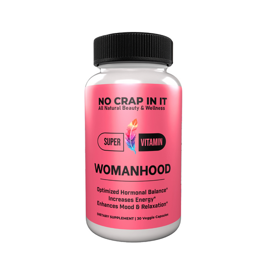 A bottle of 'No Crap In It' Womanhood Super Vitamin Supplement with pink label, black cap, and text indicating optimized hormonal balance, increased energy, and enhanced mood and relaxation.